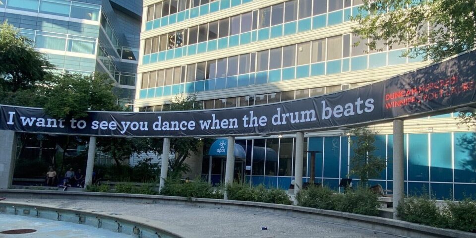 Large black banner with the words "I want to see you dance when the drum beats" installed at Air Canada Park.